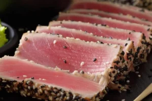 Un medallón de atún perfectamente sellado y rebanado en un plato.