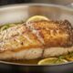 Filete de pescado Blanco del Nilo sellado en una sartén, mostrando la piel dorada y crujiente.