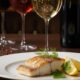 Copa de vino blanco junto a un plato de pescado sellado, demostrando un maridaje perfecto.