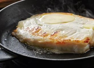 Filete de pescado blanco a la plancha dorándose en sartén de hierro fundido sin pegarse