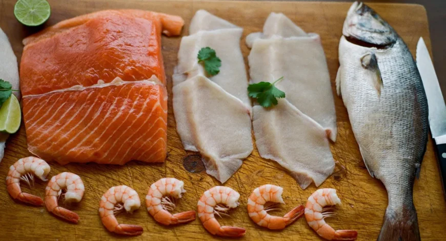 Filetes de salmón y pescado blanco, pescado entero y camarones crudos sobre tabla para elegir platillo